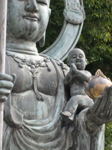 A baby perches on Jizo's arm at Taizo-in, the oldest sub-temple of Myoshin-ji. Photo © @KyotoDailyPhoto