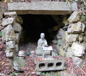 A statue of Kobo Daishi (774–835) guards a tiny hollow at Sankaku-ji representing the cave at Cape Muroto A statue of Kobo Daishi (774–835) guards a tiny hollow at Sankaku-ji representing the cave at Cape Muroto