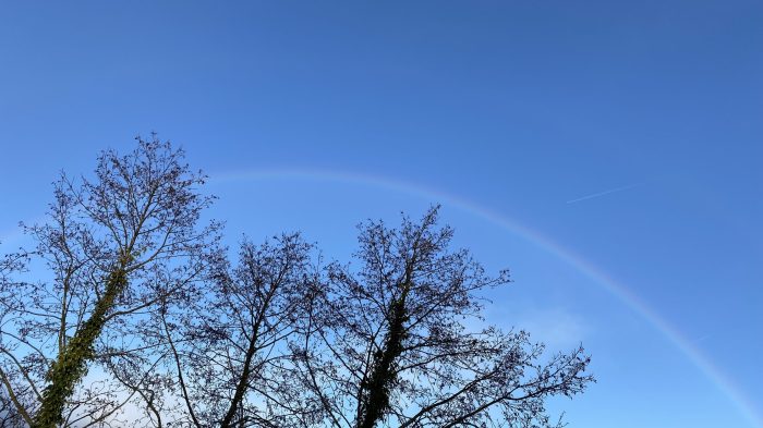 Faint rainbow in a blue sky.